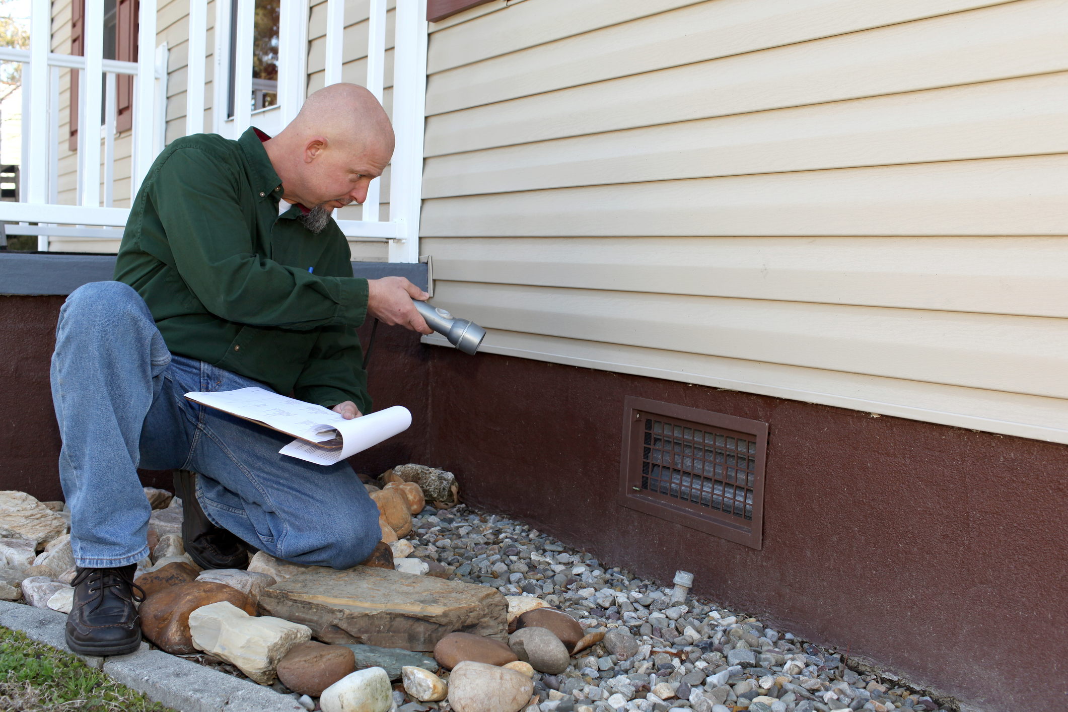 An inspector examining the foundation of a home during an estate sale inspection